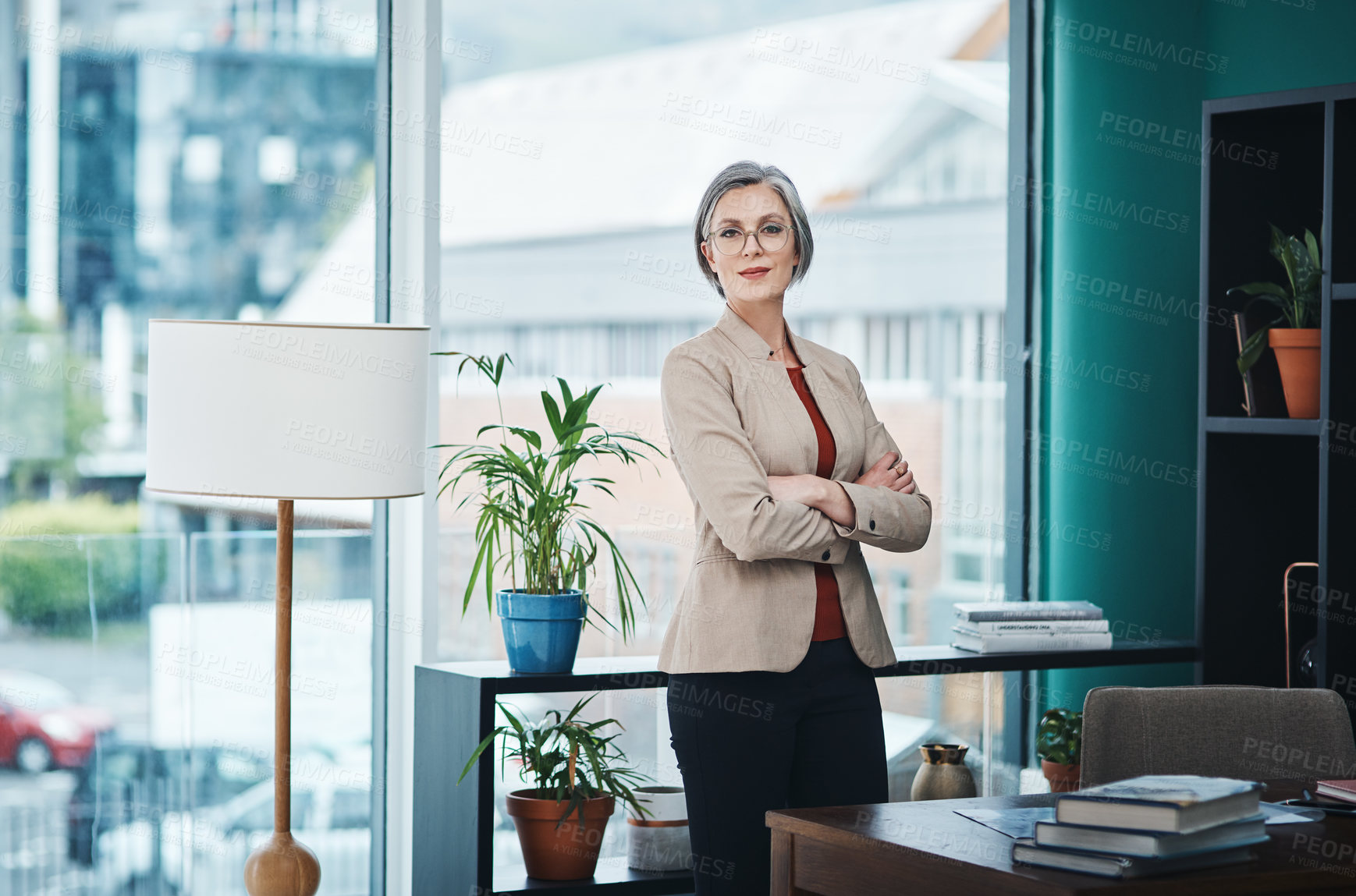 Buy stock photo Cropped portrait of an attractive mature businesswoman standing alone with her arms folded in her home office