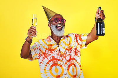 Buy stock photo Cropped shot of a funky and cheerful senior man celebrating and drinking champagne in studio against a yellow background