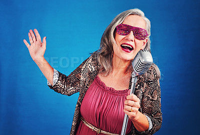 Buy stock photo Portrait of a funky and cheerful senior woman singing on a microphone in studio