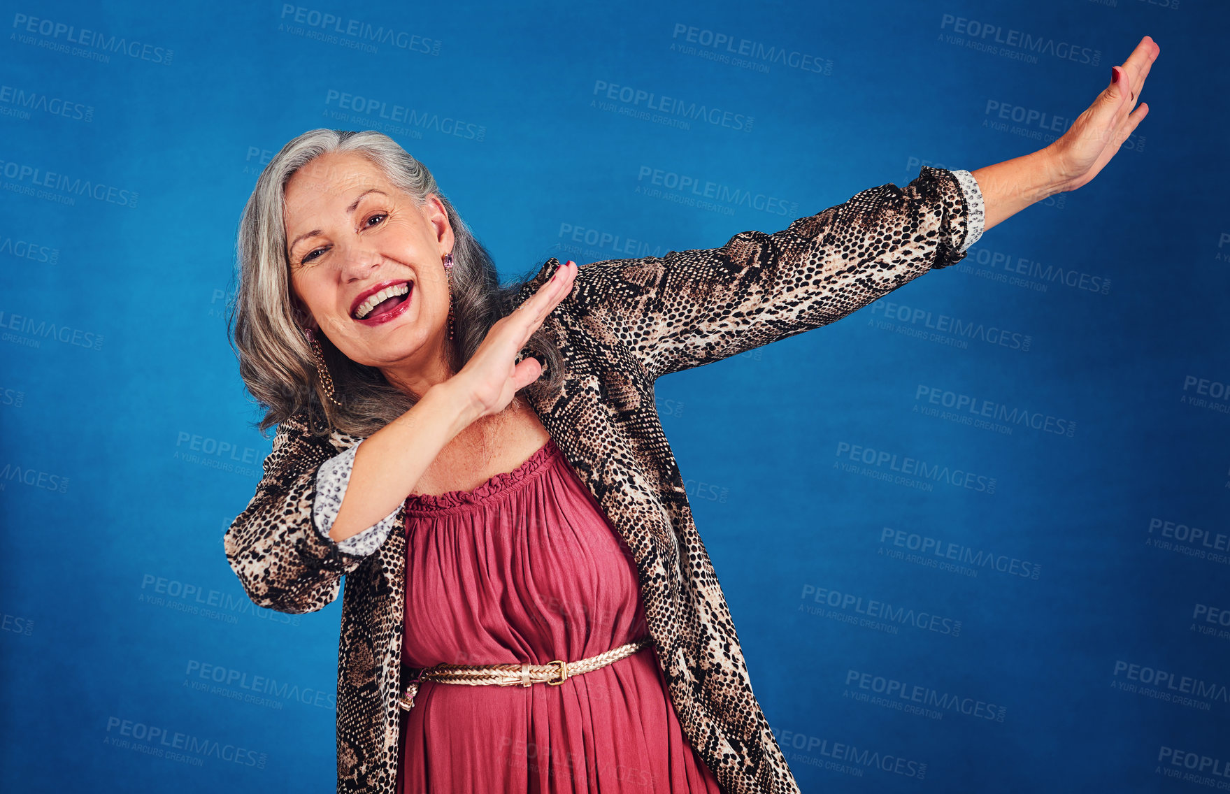 Buy stock photo Portrait of a funky and cheerful senior woman dancing in studio against a blue background