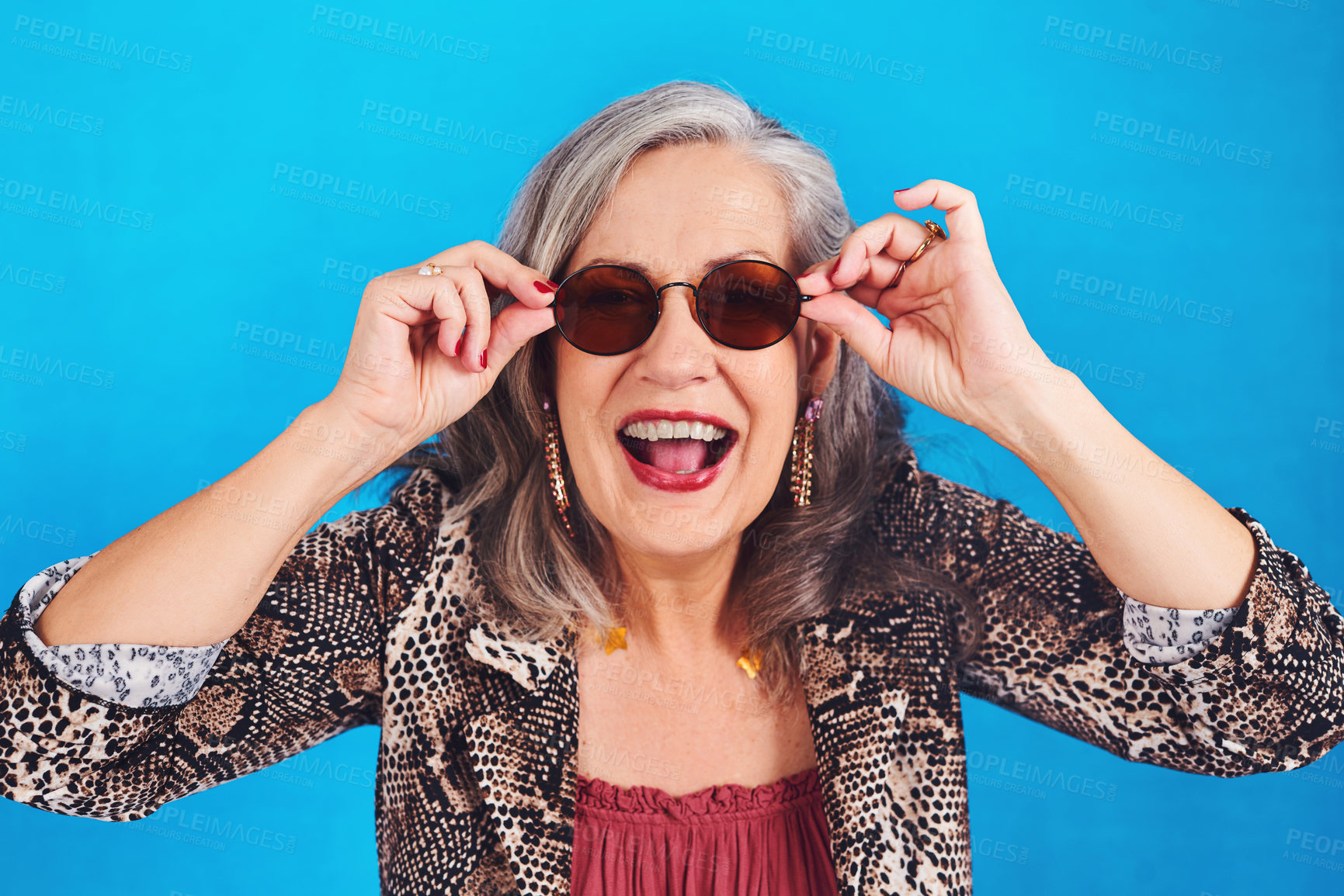 Buy stock photo Senior woman, portrait and sunglasses in studio for cool, funky and fun weekend party with happiness. Elderly person, smile and face on blue background for celebration, event and New Year concert