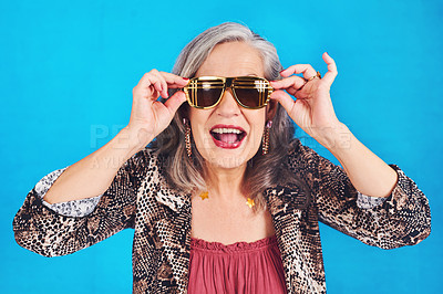 Buy stock photo Portrait of a funky and stylish senior woman wearing sunglasses posing against a blue background