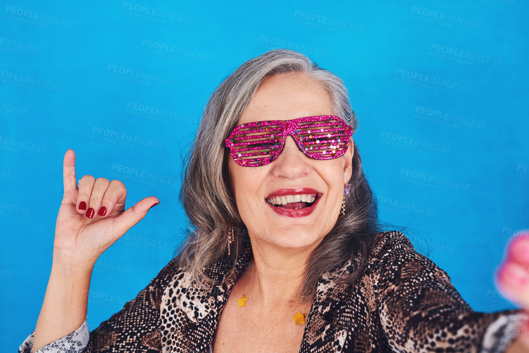 Buy stock photo Portrait of a funky and cheerful senior woman taking selfies against a blue background