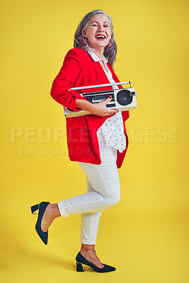 Buy stock photo Full length shot of a funky and stylish senior woman dancing while holding a boombox against a yellow background