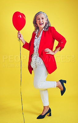 Buy stock photo Full length shot of a funky and stylish senior woman posing while holding a balloon in studio