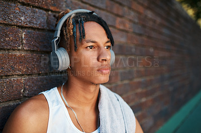 Buy stock photo Shot of a sporty young man listening to music outdoors