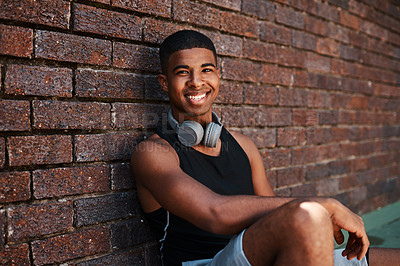 Buy stock photo Portrait of a sporty young man sitting against a wall outdoors