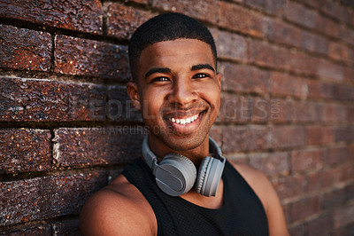 Buy stock photo Portrait of a sporty young man sitting against a wall outdoors