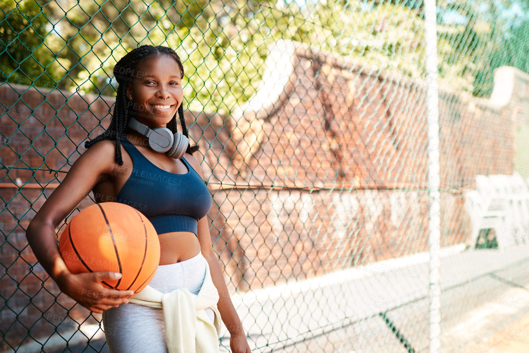 Buy stock photo Black woman, basketball court and happy in portrait with ball as athlete for challenge or exercise. Female person, headphones and fence for competition, match or game for sports or training as player