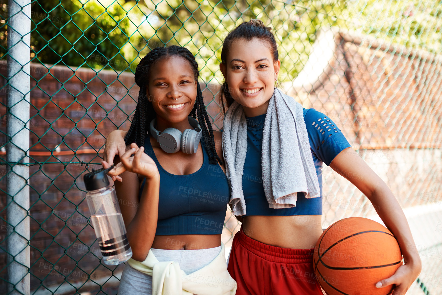Buy stock photo Portrait of two sporty young women standing against a fence on a sports court