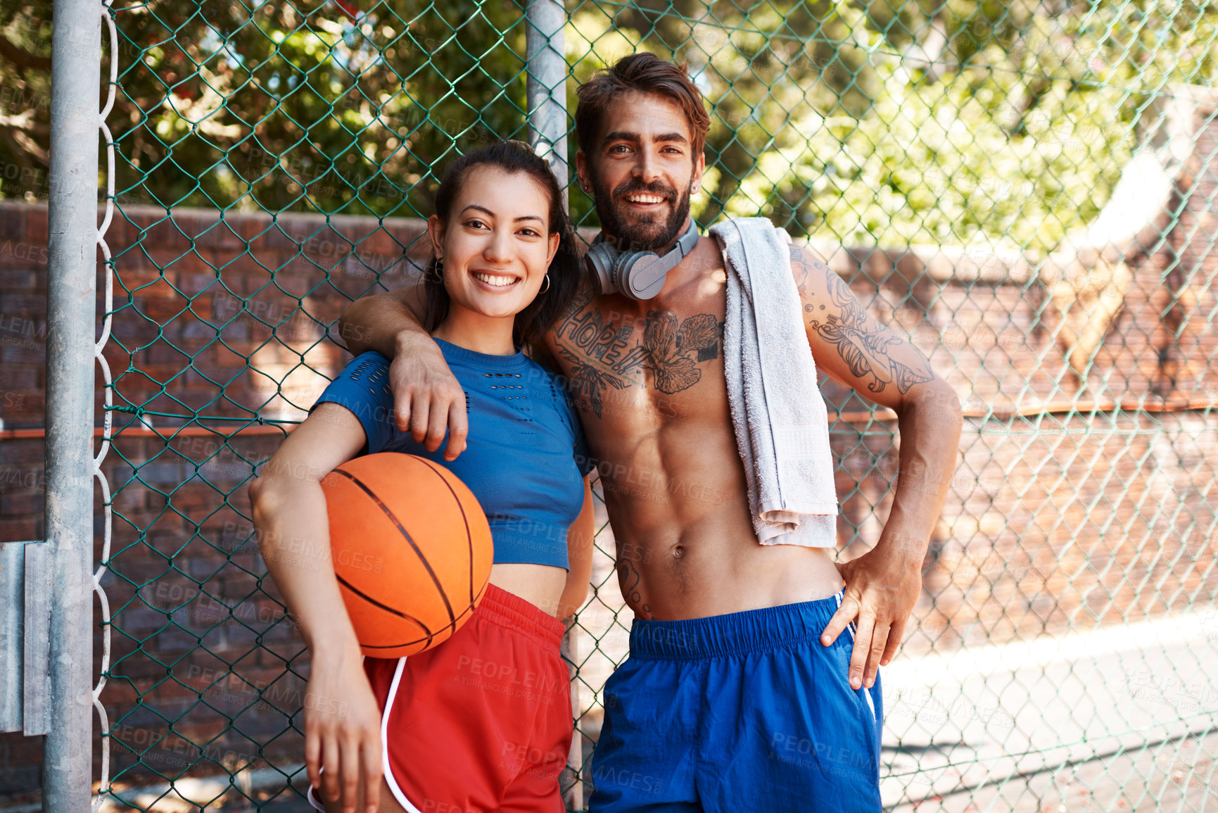Buy stock photo Portrait of two sporty young people standing against a fence on a sports court