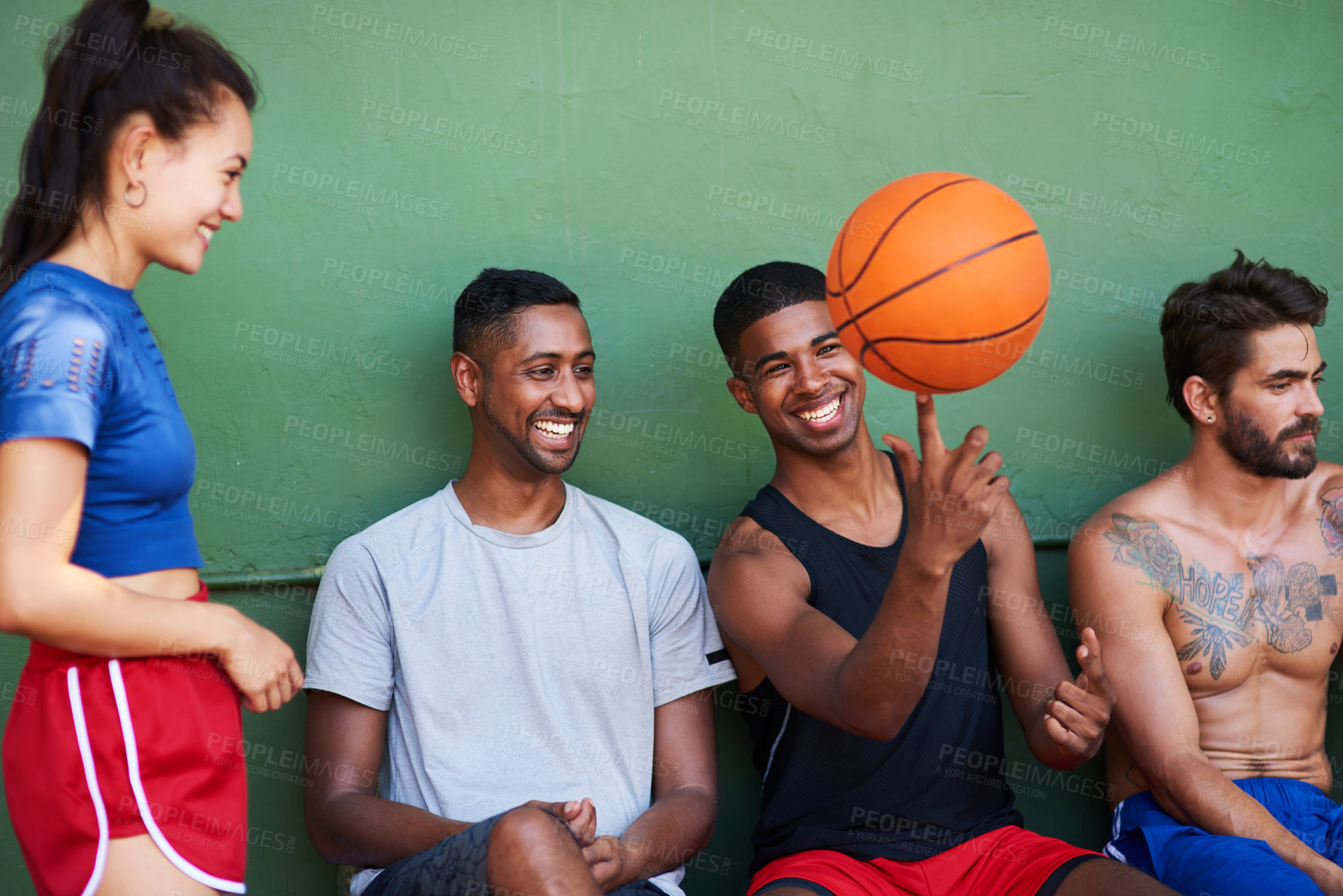 Buy stock photo Shot of a group of sporty young people taking a break after a game of basketball