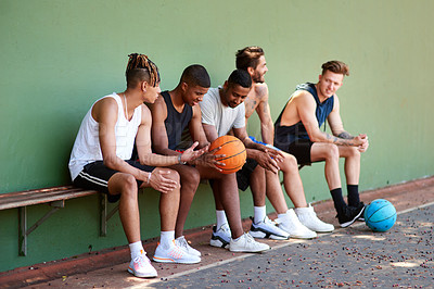 Buy stock photo Shot of a group of sporty young men taking a break after a game of basketball
