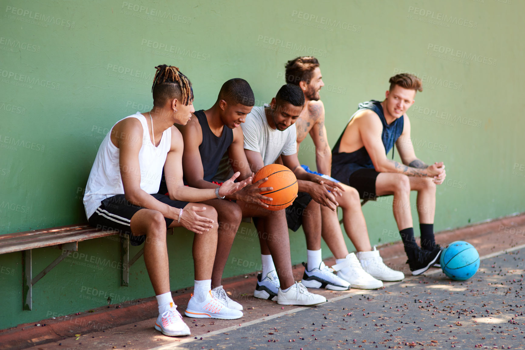 Buy stock photo Shot of a group of sporty young men taking a break after a game of basketball