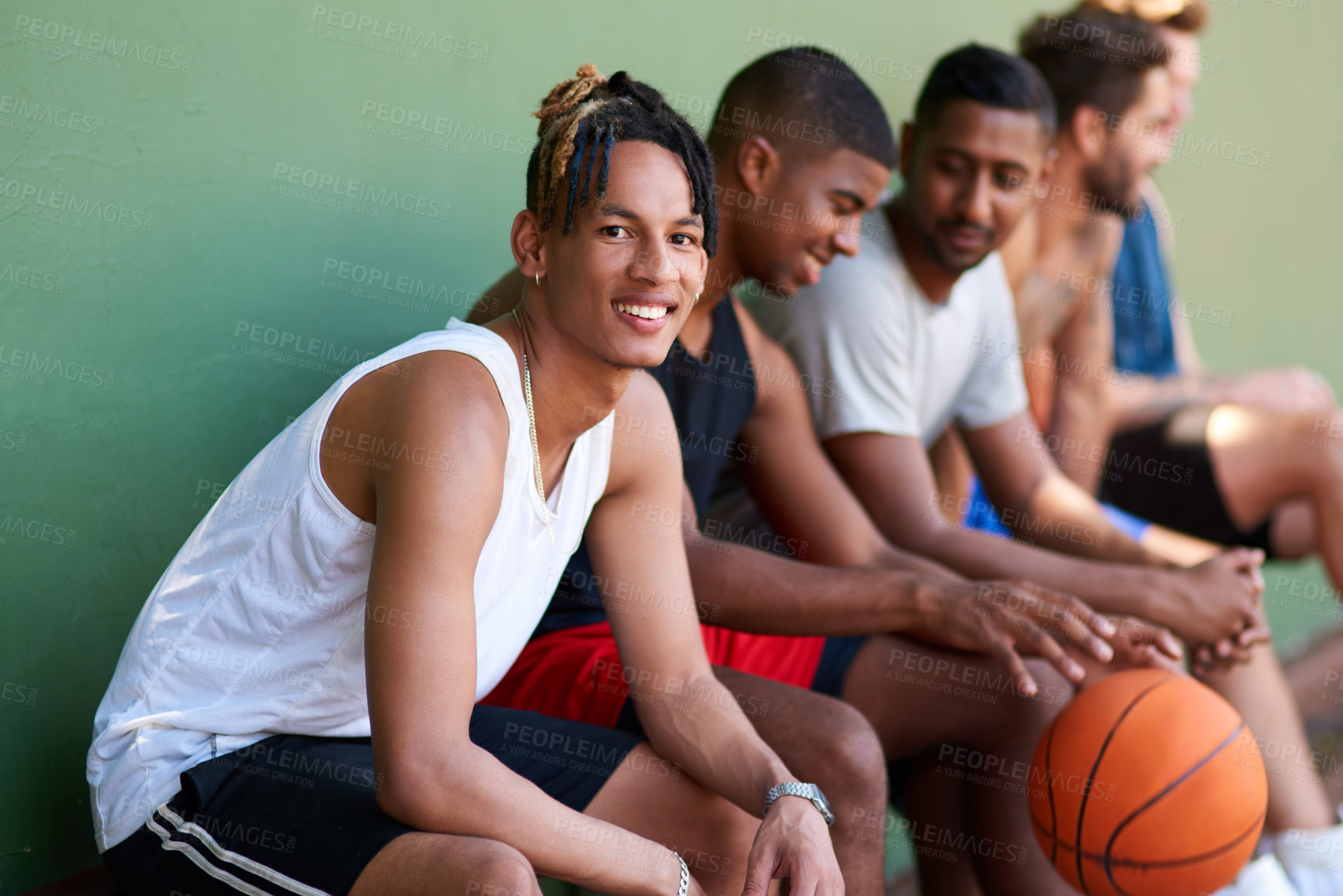 Buy stock photo Portrait of a sporty young man taking a break with his friends after a game of basketball