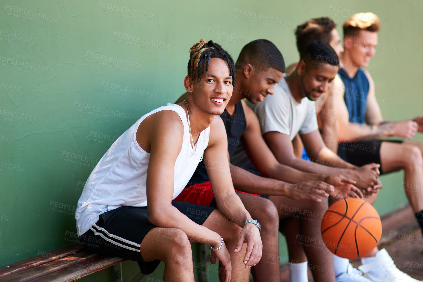 Buy stock photo Portrait of a sporty young man taking a break with his friends after a game of basketball