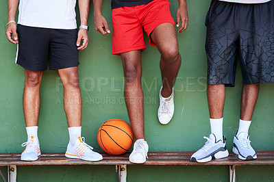 Buy stock photo Closeup shot of a group of sporty men standing on a bench alongside a basketball against a wall