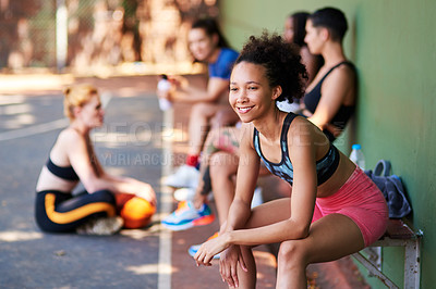 Buy stock photo Shot of a sporty young woman taking a break with her friends on a sports court