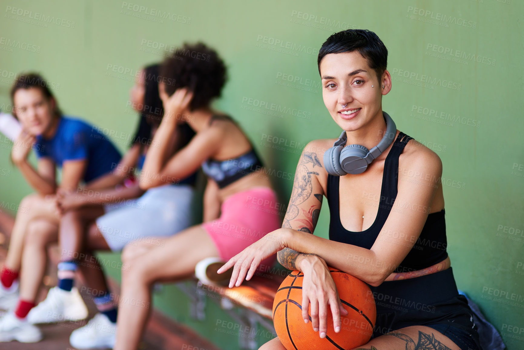 Buy stock photo Portrait of a sporty young woman taking a break with her friends after a game of basketball