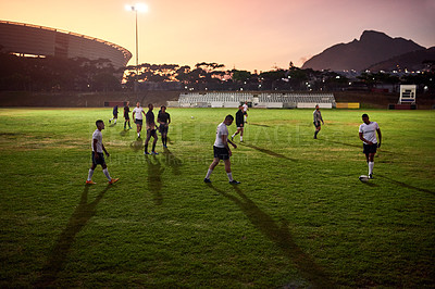 Buy stock photo Full length shot of a diverse group of sportsmen playing rugby at dusk in a sports club