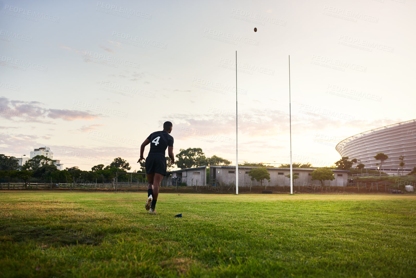 Buy stock photo Full length shot of an unrecognizable sportsman kicking a rugby ball during an early morning training session