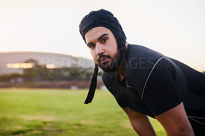 Buy stock photo Cropped portrait of a handsome young sportsman wearing headgear and crouching alone during rugby practice during the day
