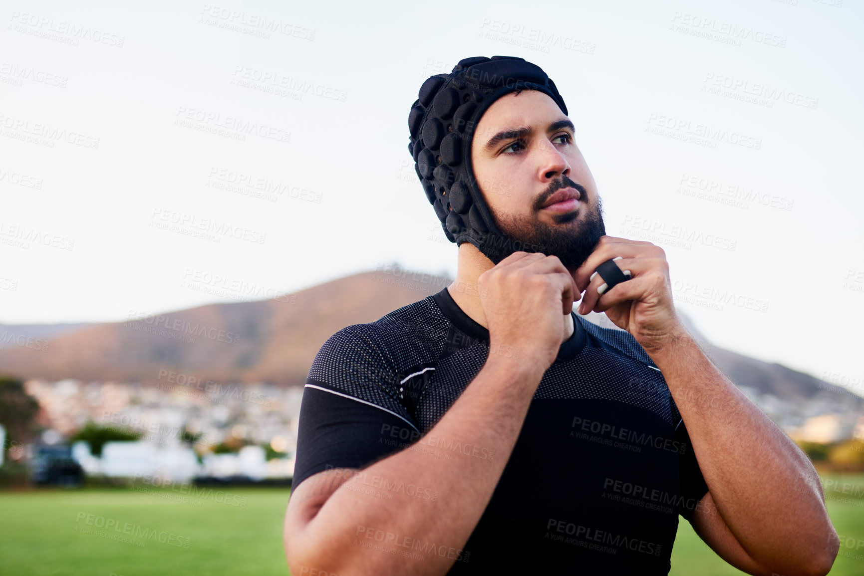 Buy stock photo Cropped shot of a handsome young sportsman wearing headgear and standing alone during rugby practice during the day