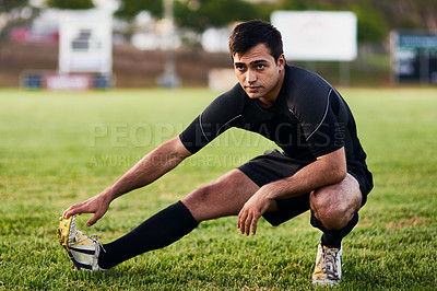 Buy stock photo Full length shot of a handsome young sportsman stretching alone before a rugby practice during the day