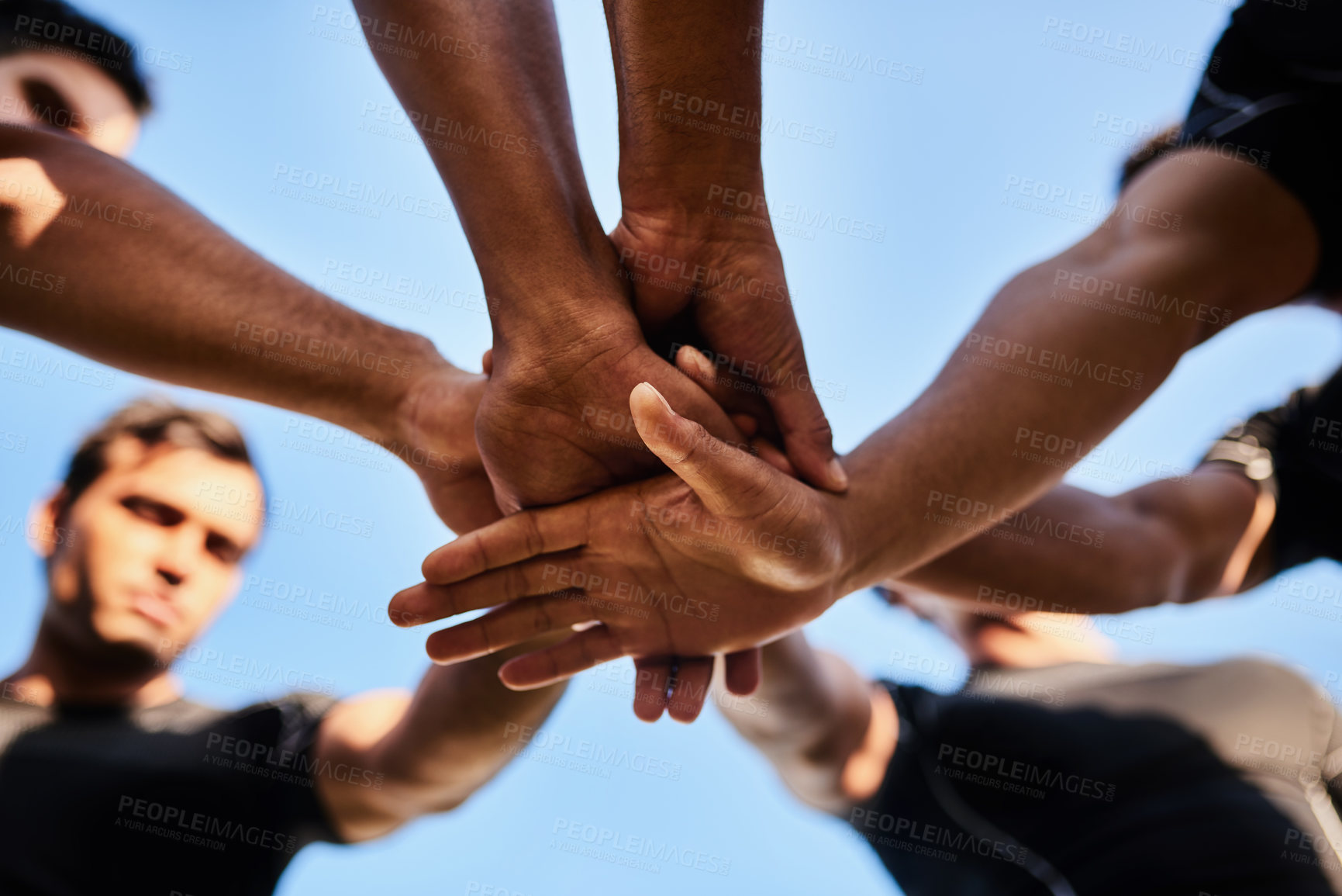 Buy stock photo Cropped shot of a handsome group of sportsmen huddled together with their hands in the middle before playing rugby