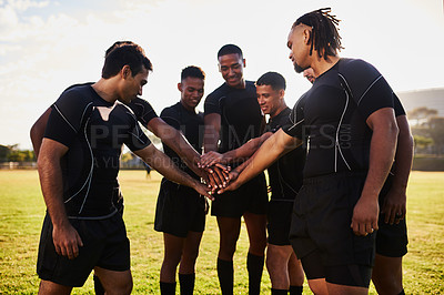 Buy stock photo Cropped shot of a handsome group of sportsmen huddled together with their hands in the middle before playing rugby