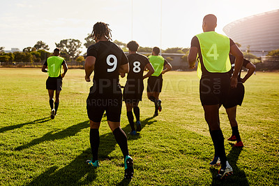 Buy stock photo Full length shot of an unrecognizable group of sportsmen warming up before playing rugby during the day