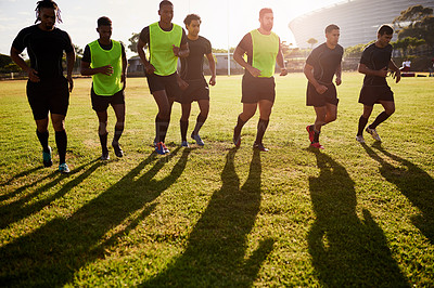 Buy stock photo Full length shot of a diverse group of sportsmen warming up before playing rugby during the day