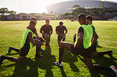 Buy stock photo Full length shot of a diverse group of sportsmen stretching before a rugby practice during the day