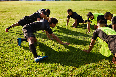 Buy stock photo Cropped shot of a diverse group of sportsmen stretching before a rugby practice during the day