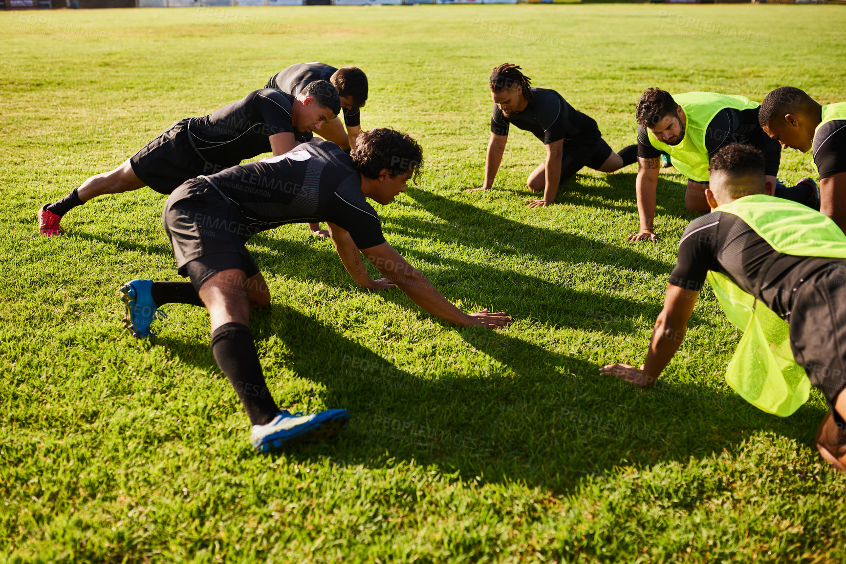 Buy stock photo Cropped shot of a diverse group of sportsmen stretching before a rugby practice during the day