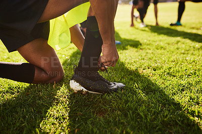 Buy stock photo Cropped shot of an unrecognizable young sportsman tying his shoelaces before playing rugby during the day