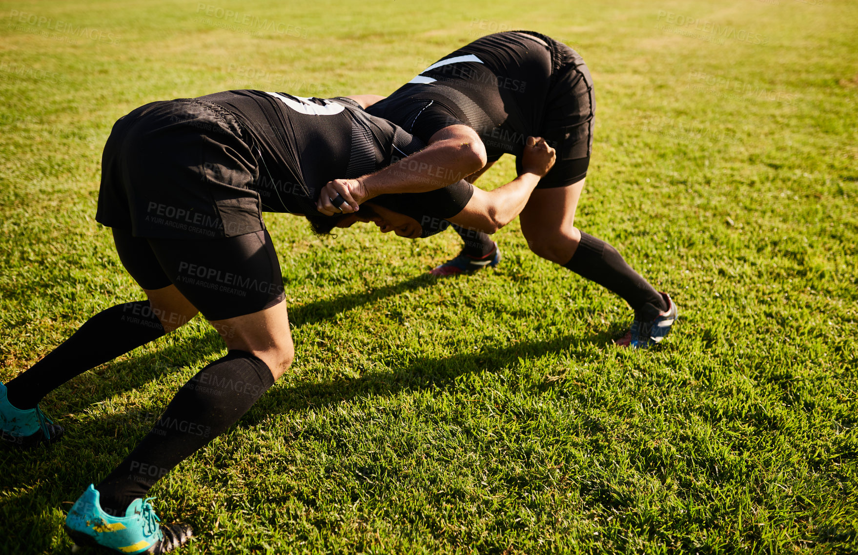 Buy stock photo Full length shot of two unrecognizable sportsmen tacking each other during a rugby game during the day