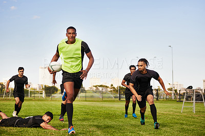 Buy stock photo Full length shot of a diverse group of sportsmen playing a game of rugby during the day