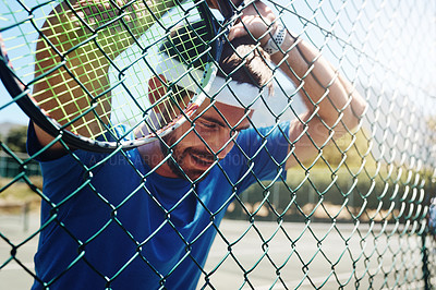 Buy stock photo Cropped shot of a handsome young sportsman taking a moment to breathe during tennis practise