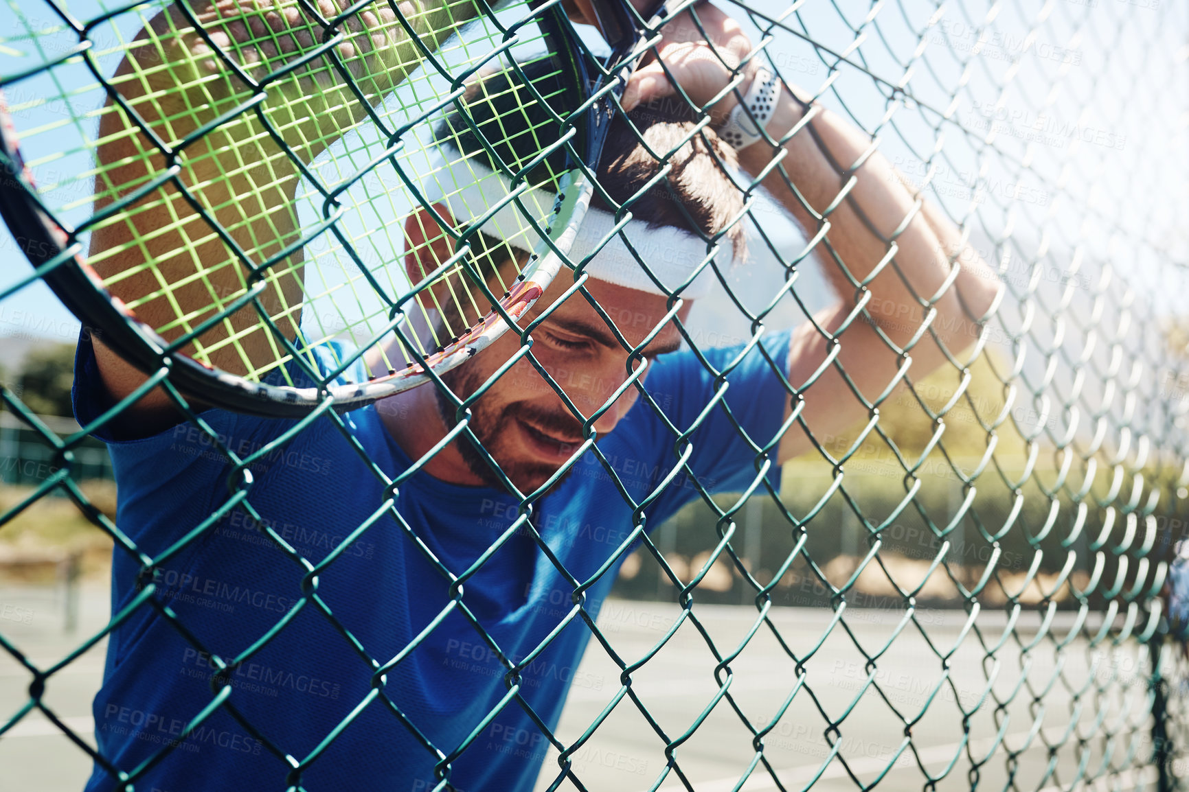 Buy stock photo Cropped shot of a handsome young sportsman taking a moment to breathe during tennis practise