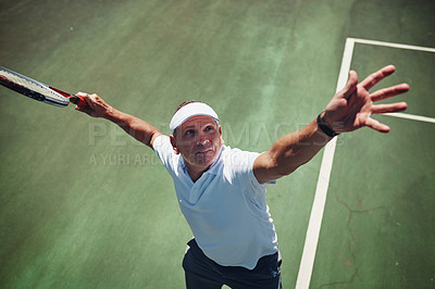 Buy stock photo High angle shot of a handsome mature sportsman playing tennis alone on a court during the day