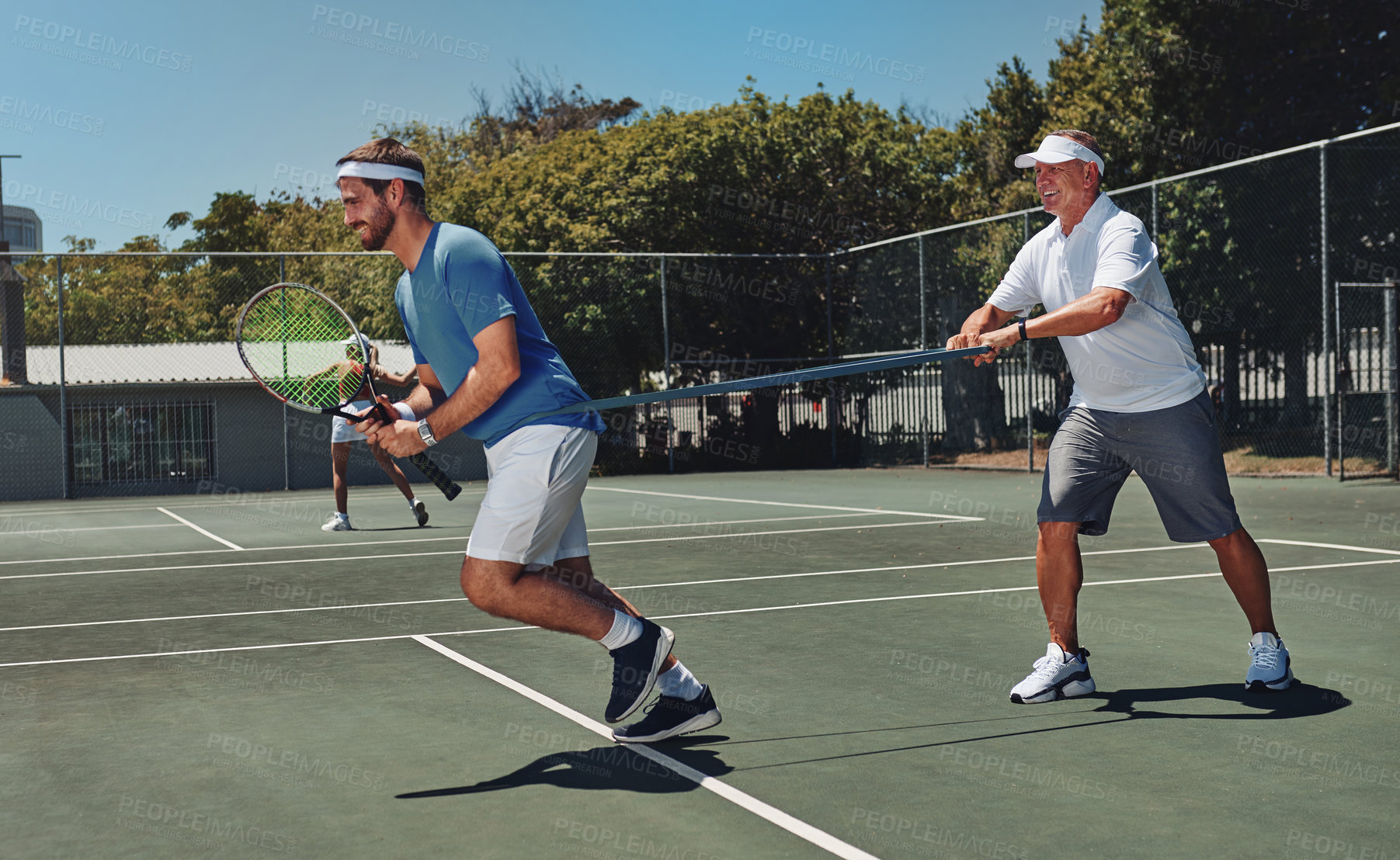 Buy stock photo Full length shot of two handsome sportsmen using resistant bands during a tennis training session during the day