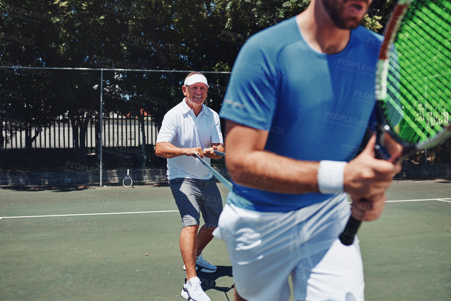 Buy stock photo Cropped shot of two handsome sportsmen using resistant bands during a tennis training session during the day