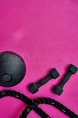 Buy stock photo High angle shot of two lightweight dumbbells and piece of rope placed on a pink background inside of a studio
