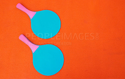 Buy stock photo High angle shot of two table tennis bats placed together on top of an orange background inside of a studio