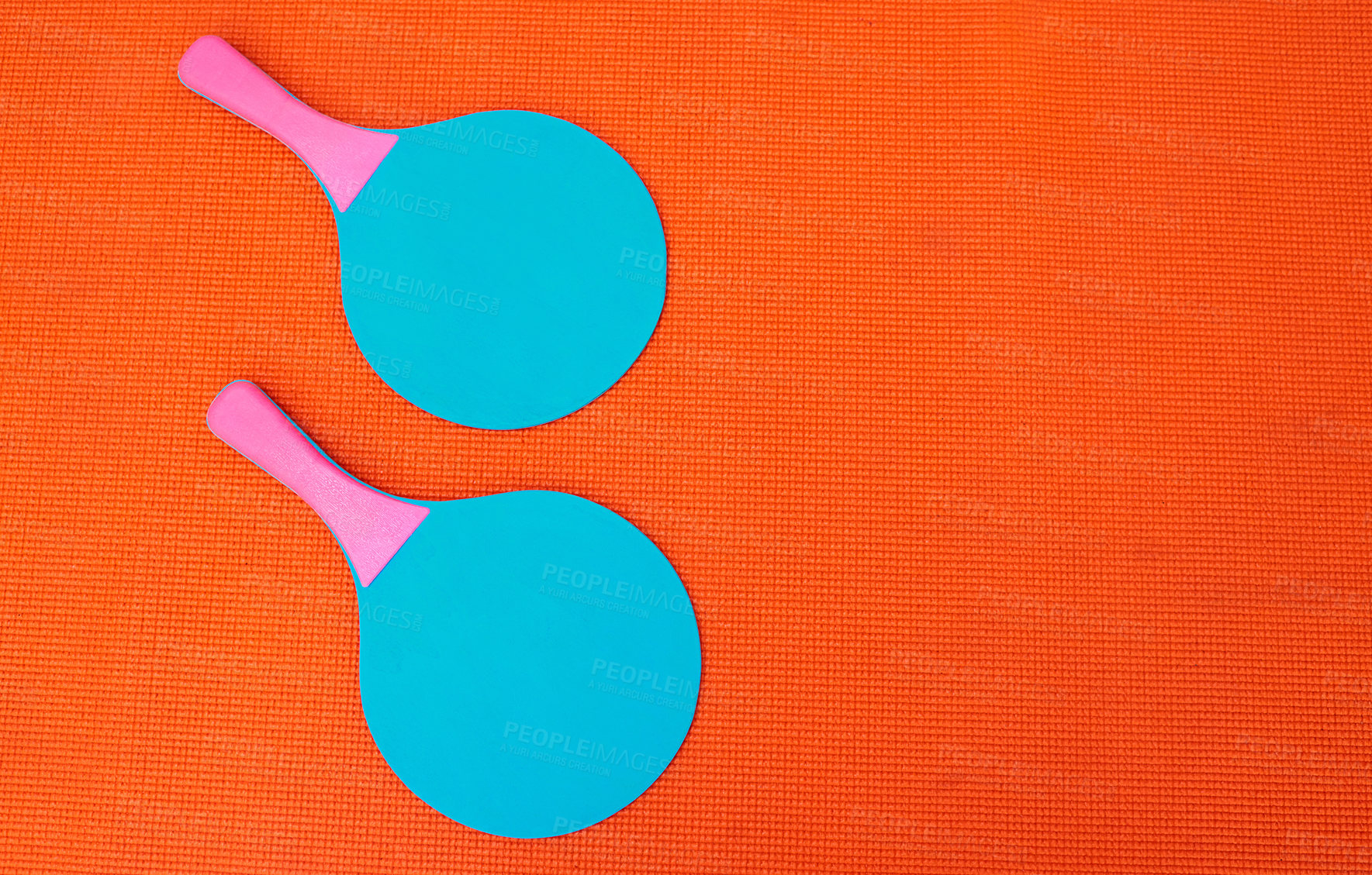 Buy stock photo High angle shot of two table tennis bats placed together on top of an orange background inside of a studio