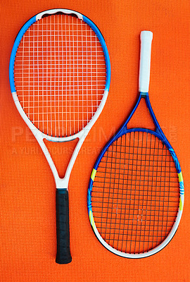 Buy stock photo High angle shot of two tennis rackets placed on an orange background inside of a studio