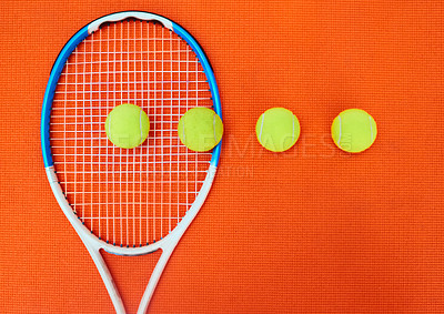 Buy stock photo High angle shot of a single tennis racket and a few tennis balls placed on an orange background inside of a studio