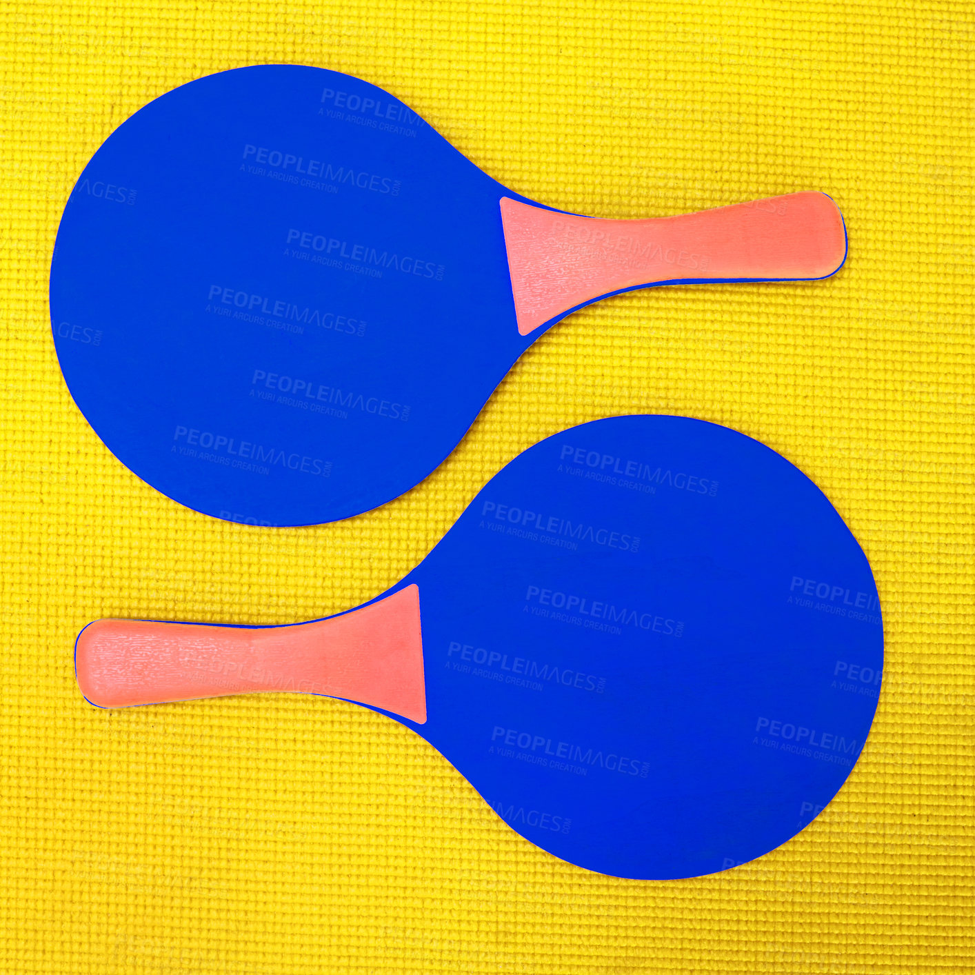 Buy stock photo High angle shot of two blue table tennis rackets placed on top of a yellow background inside of a studio