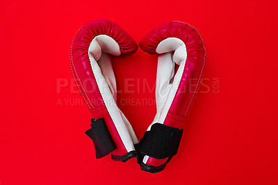 Buy stock photo High angle shot of a pair of boxing gloves placed together on top of a red background inside of a studio